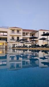 a hotel with tables and umbrellas and a swimming pool at NS Apartments Nydri in Nydri