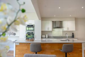 a kitchen with white cabinets and a counter with two chairs at Aughamore Home in CBG