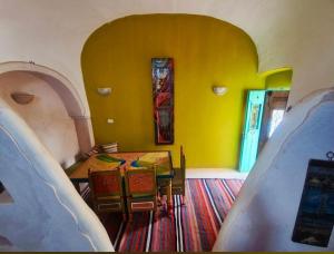a dining room with a table and a yellow wall at Chambre dans une maison d'hôtes in Medenine