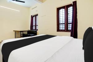 a bedroom with a white bed and two windows at Hotel O Nakshathra Inn in Kazhakuttam +25 photos
