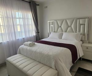a white bedroom with a large bed and a window at 2 Bed Cottage close to Westgate Shopping Centre in Harare