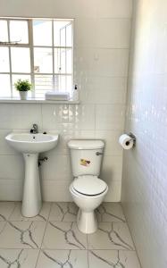 a white bathroom with a toilet and a sink at 2 Bed Cottage close to Westgate Shopping Centre in Harare +11 photos