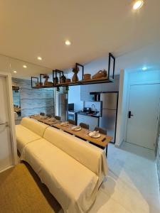 a living room with a long couch and a kitchen at Infinity 1206 - 2 Quartos a Passos da Praia com Garagem in Vila Velha +26 photos