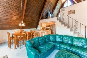 a living room with a green couch and a kitchen at Charming, lakefront A-frame with private dock, lakeside gazebo, spacious deck in Bumpass
