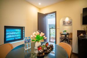 a dining room with a glass table with flowers on it at DoDo Apartments in Hanoi