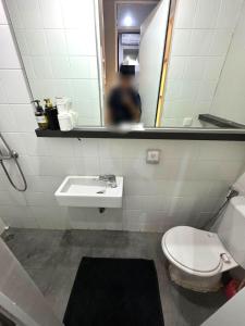 a bathroom with a toilet and a sink and a mirror at Comfortable House - Tabebuya BSD in Tegal