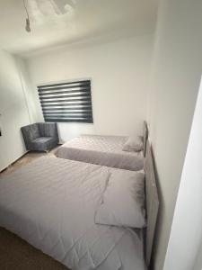 a bedroom with two beds and a chair at Neue renovierte Wohnung mit Meerblick und große Balkon in tripoli ,Qalamoun in El Qalmoûn