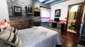 a bedroom with a bed and a stone wall at Casona El Gurugu in Luarca