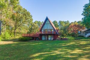 a house with a gambrel roof on a lawn at Charming, lakefront A-frame with private dock, lakeside gazebo, spacious deck in Bumpass