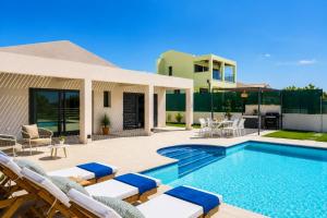 a swimming pool with chairs and a house at Villa Pinelopi Tria in Kounopetra