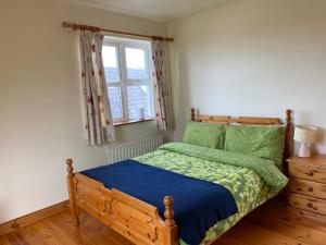 a bedroom with a wooden bed and a window at The Cliffs of Moher House, Doolin in Doolin