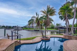a swimming pool with palm trees next to a body of water at Pet Friendly! Canal-Front Apollo Beach Gem w/ Pool in Apollo Beach