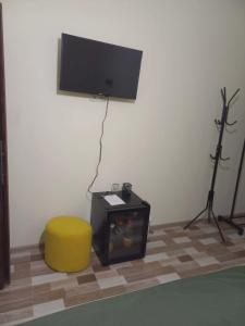 a room with a tv and a yellow stool and a table at Ani Center Hotel in Dovekh