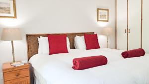 a bedroom with a large white bed with red pillows at Cruise Cottage in Stanford