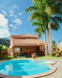 una piscina frente a una casa con palmeras en Villa Tauro Country Club, en La Playa de Tauro