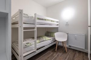ein Schlafzimmer mit zwei Etagenbetten und einem Stuhl in der Unterkunft Harzer-Geißen Lounge in Hohegeiß