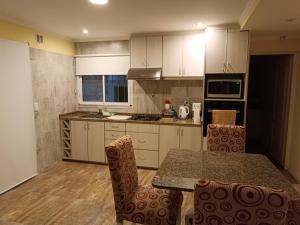 a kitchen with white cabinets and a table and chairs at Melo 2203 Duplex 1 in Belén de Escobar