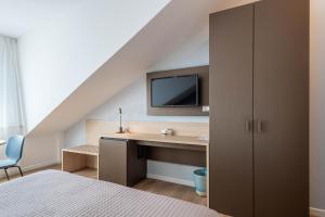 a bedroom with a desk and a tv on the wall at Hotel Caracas in Lignano Sabbiadoro