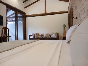 a bedroom with a white bed and a couch at Vila Natholi Hotel Boutique in Imbassai +35 photos