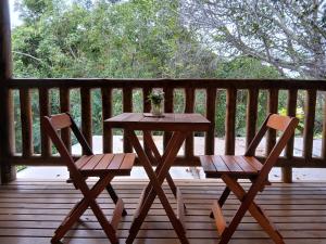 a wooden table and two chairs on a deck at Vila Natholi Hotel Boutique in Imbassai