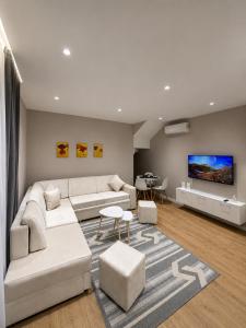 a living room with white furniture and a flat screen tv at ODA Central Stay in Elbasan