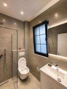 a bathroom with a toilet and a sink and a window at ODA Central Stay in Elbasan +15 photos