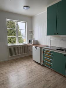 an empty kitchen with green cabinets and a window at Apartment Målargården in Uddeholm