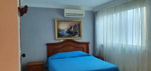 a bedroom with a blue bed and a painting on the wall at HOTEL VASCONIa in Cúcuta