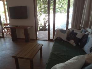 a living room with a couch and a table and a television at Vila Natholi Hotel Boutique in Imbassai