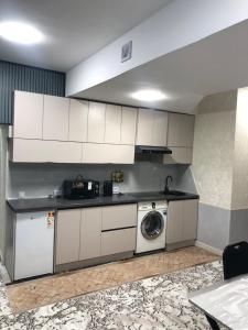 a kitchen with white cabinets and a washing machine at Studio - JONIKA in Tashkent