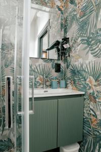 a bathroom with a green sink and tropical wallpaper at Domo De Uccio in Alghero