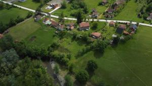 eine Gruppe von Häusern auf einem Feld mit einem Fluss in der Unterkunft Vikendica Nik in Bogutovac