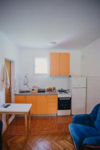 eine Küche mit orangefarbenen Schränken und einem blauen Sofa in der Unterkunft Vikendica Nik in Bogutovac