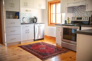 a kitchen with white cabinets and a rug on the floor at Triangle de l'île Chambre le Grenier in Saint-Laurent-de-l'ile d'Orleans +5 photos