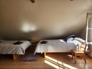 a bedroom with two beds and a chair at Triangle de l'île Chambre le Grenier in Saint-Laurent-de-l'ile d'Orleans