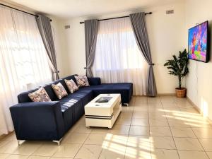 a living room with a blue couch and a table at 2 Bed Cottage close to Westgate Shopping Centre in Harare