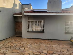 a white house with a window and a driveway at 2 Bed Cottage close to Westgate Shopping Centre in Harare