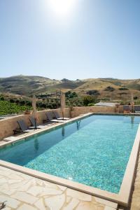 a large swimming pool with chairs and a mountain in the background at Lavender Suite in Paránimfoi