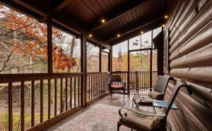 a screened in porch with two chairs and a table at Bearadise Hot Tub 6 Min to The Island in Pigeon Forge