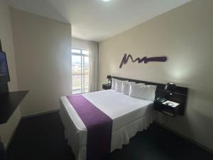 a bedroom with a large bed with a purple blanket at Vista Inn Express Contagem in Contagem