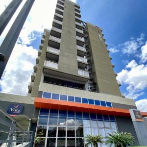 a tall building with palm trees in front of it at Vista Inn Express Contagem in Contagem