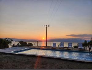 a swimming pool with two chairs and a sunset at CHRIS sopo in Elshani