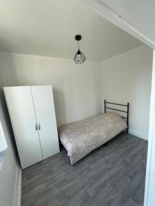 a white bedroom with a bed and a cabinet at Appartement 2 in Vireux-Wallerand