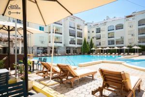 a hotel pool with chairs and an umbrella at Joni's Twin Condos (Pool&Pine View) in Golem