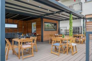 a restaurant with wooden tables and chairs on a deck at Apartments Bukor with seasonal pool in Lukovica pri Domžalah