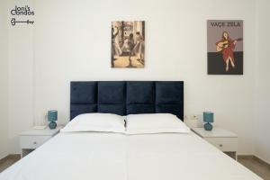 a bedroom with a white bed with two posters on the wall at Joni's Twin Condos (Pool&Pine View) in Golem +56 photos