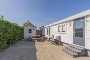 a patio with two chairs and a table next to a trailer at Chaletparc Krabbenkreek Zeeland - Chalet 96 in Sint Annaland