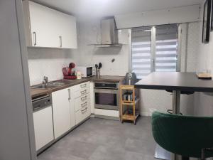 a small kitchen with white cabinets and a table at Sálvora, Illas da Pousa in Ribeira