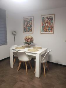 a white table with chairs and a vase with flowers at Sálvora, Illas da Pousa in Ribeira