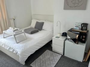 a bedroom with a white bed with a night stand at fAiRy DeLL Guesthouse 24-7 check in, cozy lockable rooms, tv, tea tray with choccies, cooling fans, free wifi and parking, COA, all are welcome in Bradford +36 photos